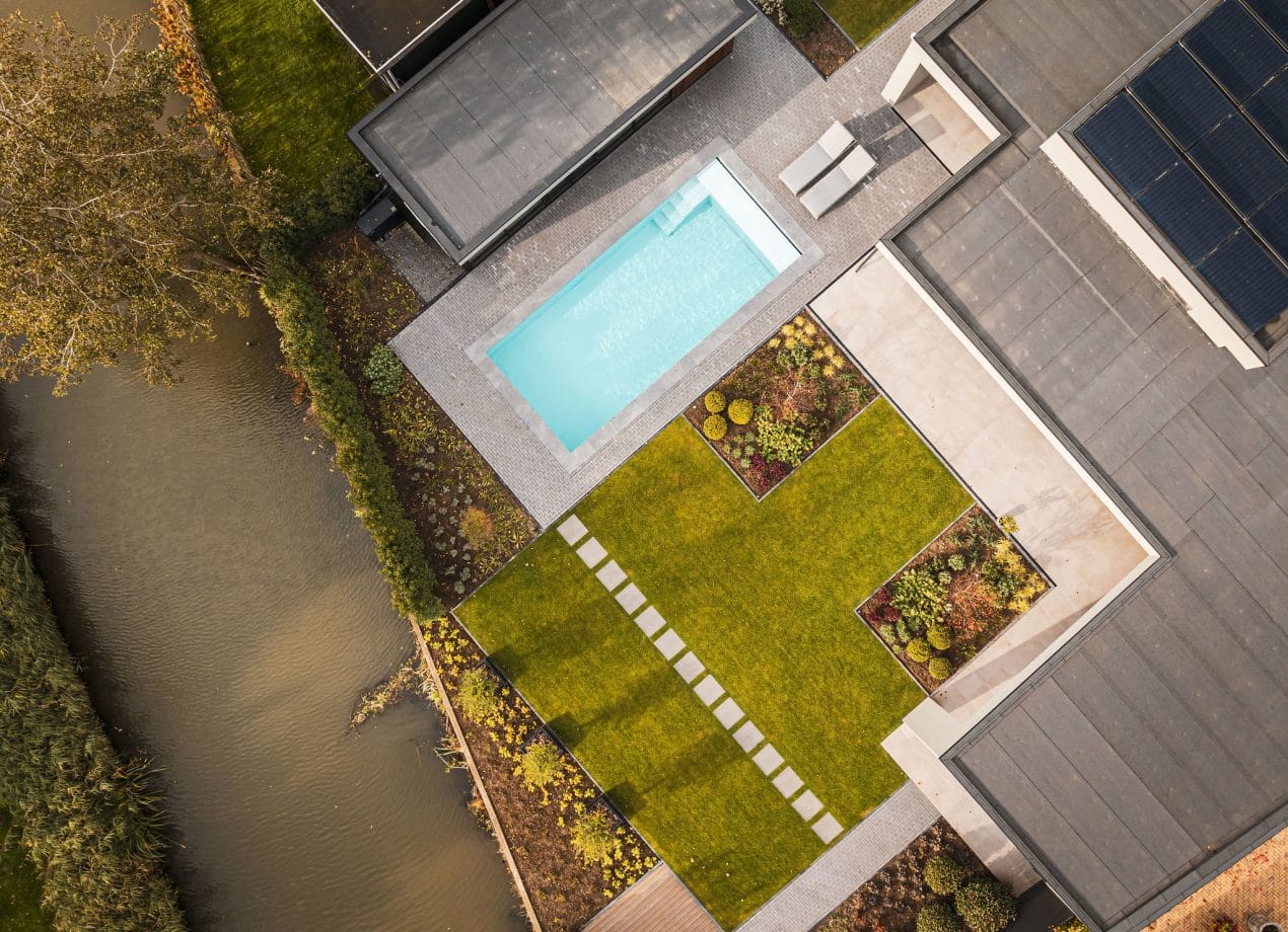 Luchtfoto van een Flexline zwembad, strak vormgegeven en luxe geïntegreerd in de tuin met heldere waterlijn.