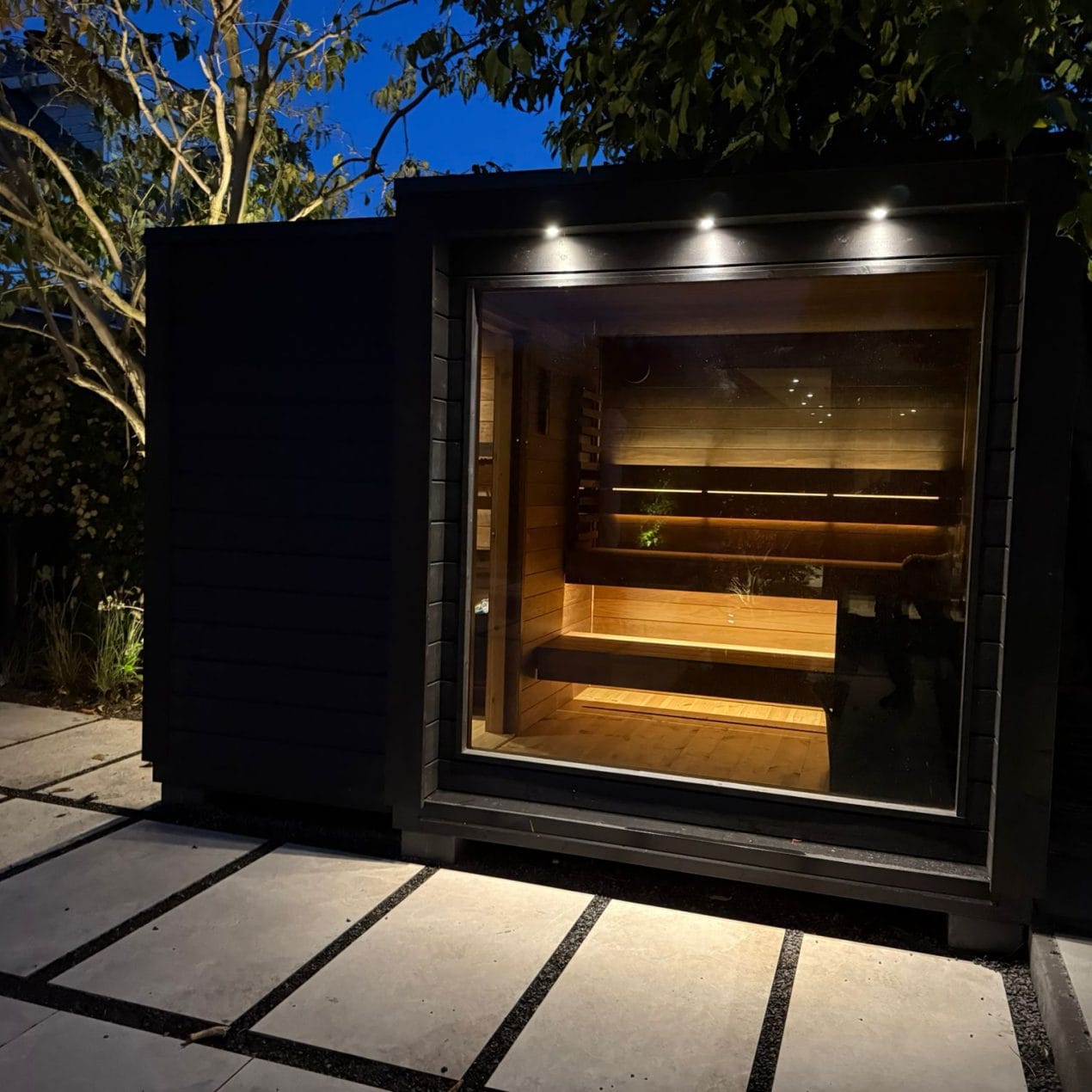 Mökki buitensauna in een tuinsetting, luxe afgewerkt met houten design en warme, natuurlijke uitstraling.