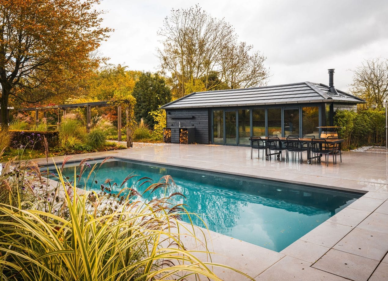 Sfeerbeeld van een LPW zwembad in de herfst, met warme tinten, vallende bladeren en een luxe, rustige uitstraling.